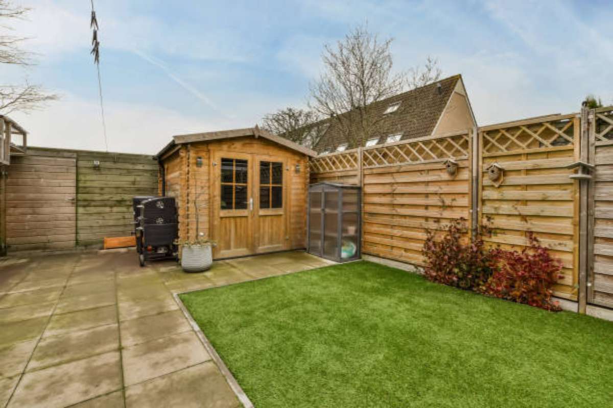 Modern pent shed with single-sloped roof beside a fence.